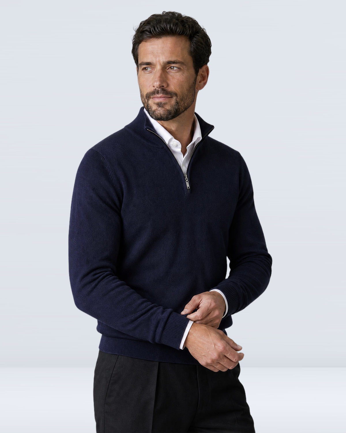 Hombre con suéter WINDSOR azul marino ajustándose el puño, vista de tres cuartos