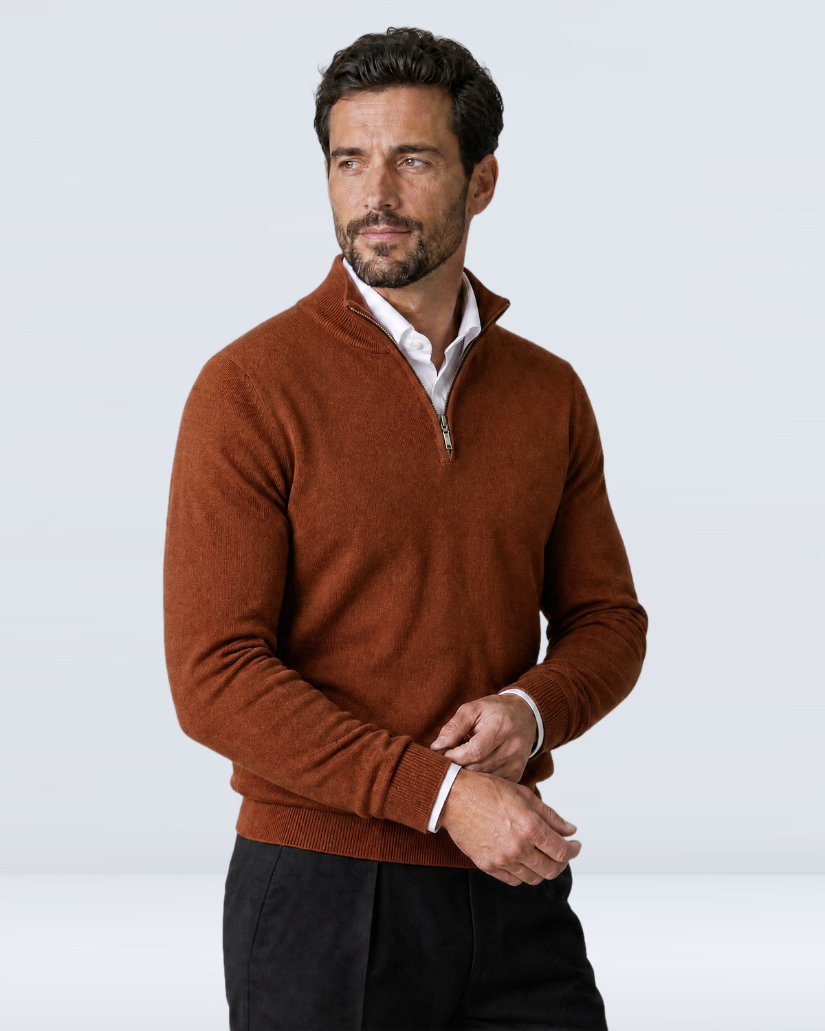 Hombre con suéter WINDSOR caramelo ajustándose el puño, vista de tres cuartos