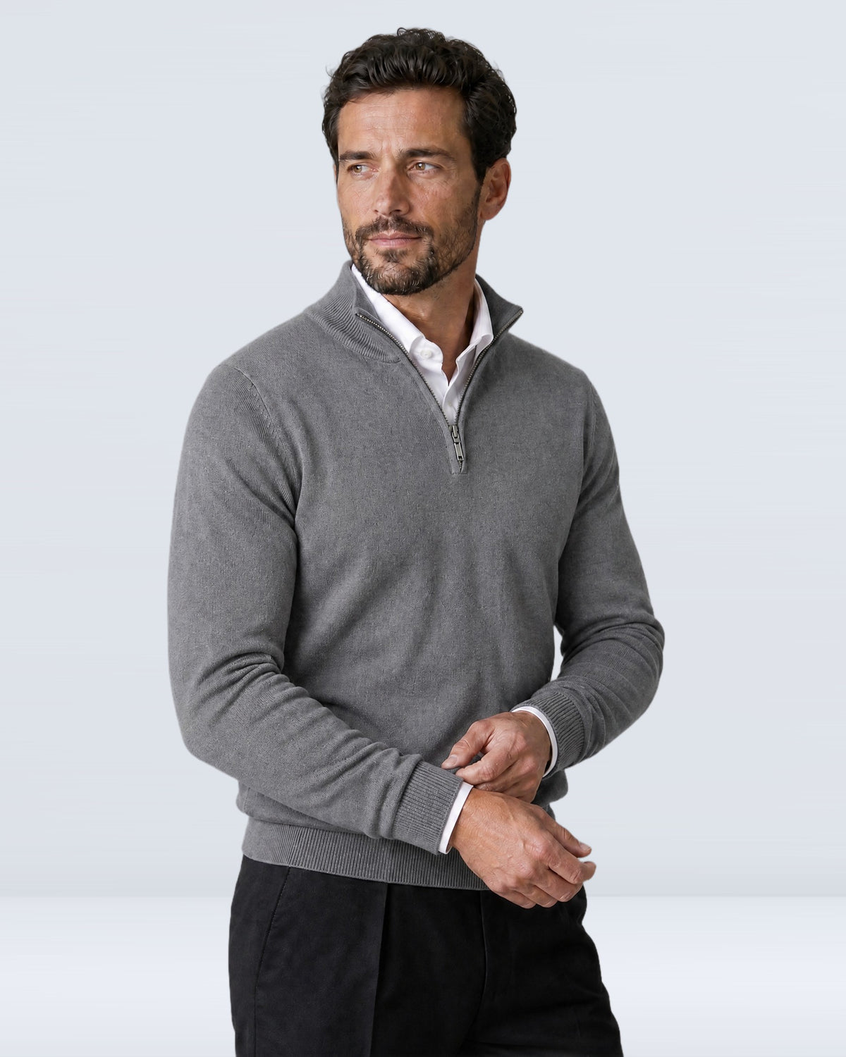 Hombre con suéter WINDSOR gris ajustándose el puño, vista de tres cuartos