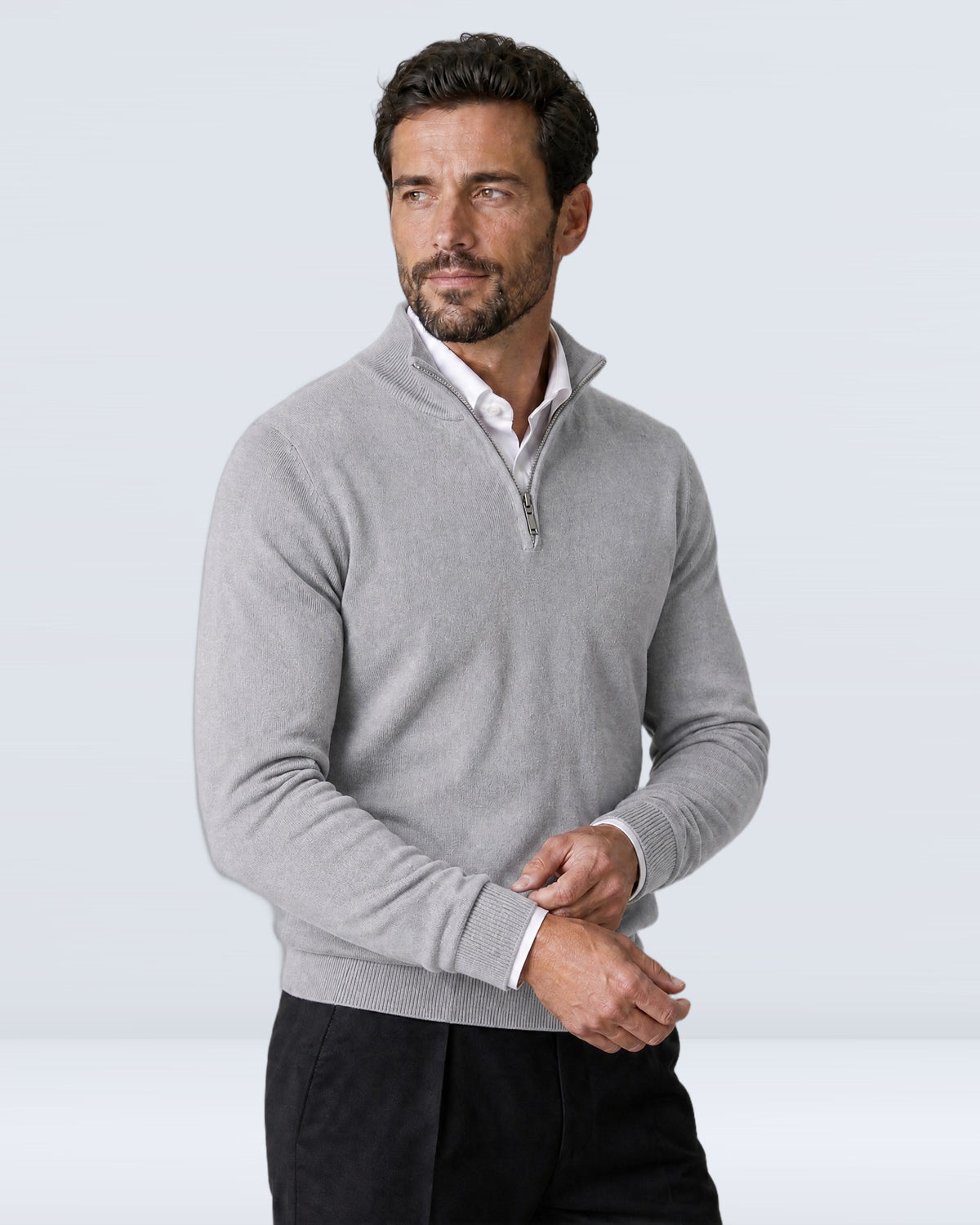 Hombre con suéter WINDSOR gris claro ajustándose el puño, vista de tres cuartos